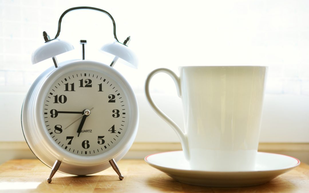 Wecker und Kaffeetasse als Symbol für Überstunden und Arbeitszeit